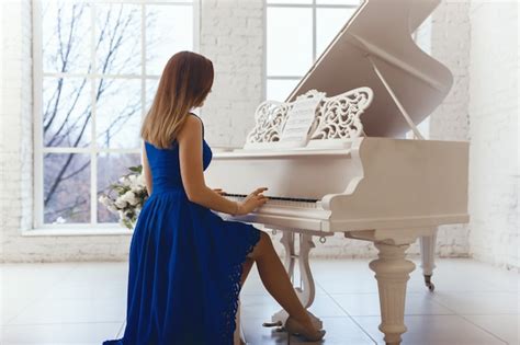 Premium Photo Woman In A Blue Evening Dress Playing On A White Piano