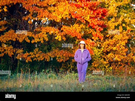 Woman Walking In Fields Surrounded By Autumn Fall Colors Stock Photo