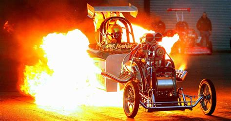 A Man Riding On The Back Of A Motorcycle With Flames Coming Out Of Its