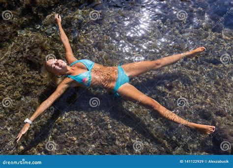 Girl With Arms Outstretched And Legs Apart Lies On Water Stock Image