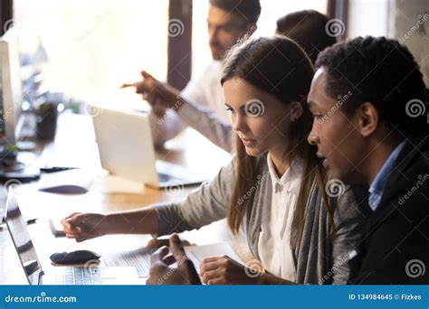 Diverse Millennial Employees Working Together Using Laptop In Of Stock