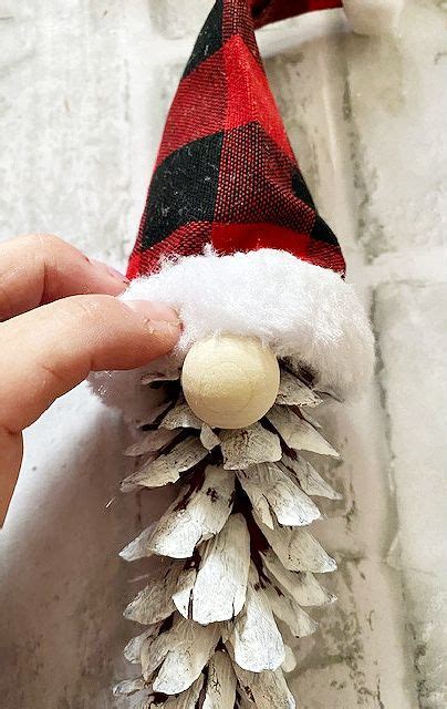A Hand Holding A Pine Cone With A Santa Hat On It