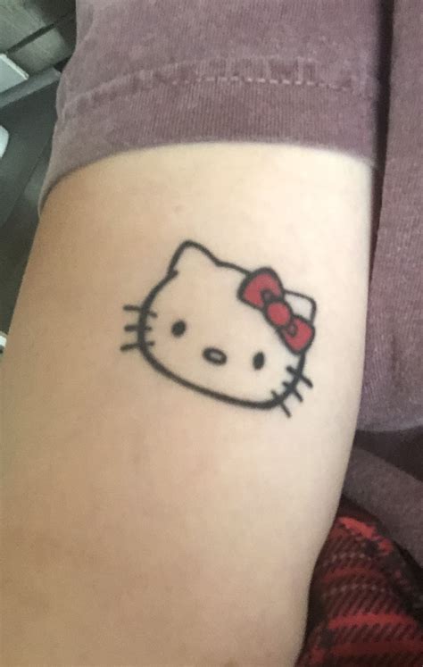 A Hello Kitty Tattoo On The Arm Of A Womans Left Leg With A Red Bow