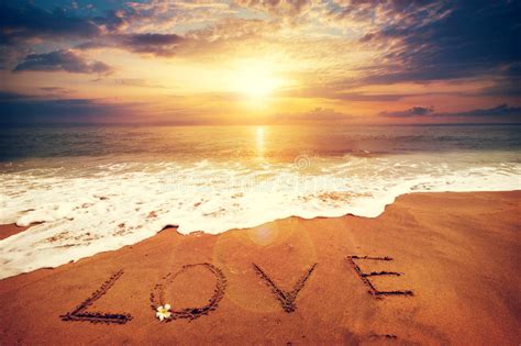 Inscription Love Written On The Sandy Beach With Ocean Wave Sunset