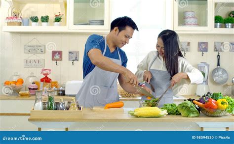 Young Asian Couple Are Teasing While Cooking In The Kitchen Stock