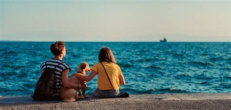 Premium Photo Mother And Daughter Sitting On The Waterfront With Dog