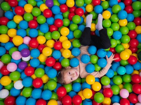 Cute Little Girl Playing On Multi Coloured Plastic Balls In Big Dry