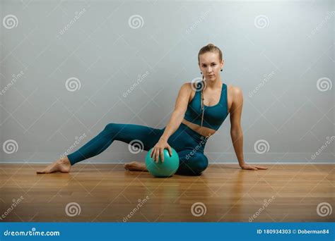 The Young Beautiful Sports Girl Doing Exercises On A Fitball At The Gym On Gray Background