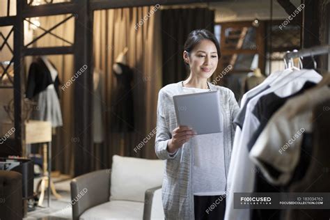 Chinese Clothing Store Owner Standing With Digital Tablet Fashionable Style Stock Photo