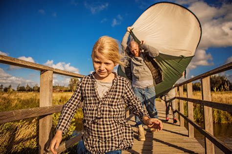 Handsome Redhead Father And Blonde Daughters Chasing A Tent Caught In The Wind On A Camping