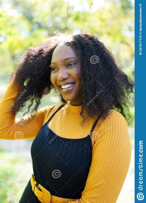 beautiful african american woman smiling and walking in the park during sunset outdoor portrait