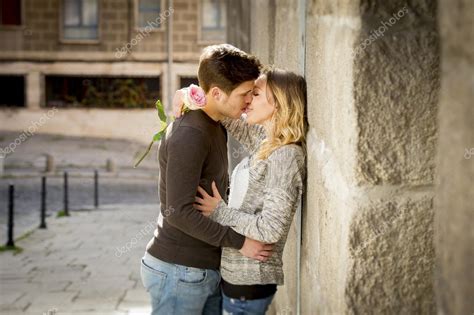 Candid Portrait Of Beautiful European Couple With Rose In Love Kissing On Street Alley