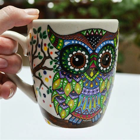 A Hand Holding A Coffee Cup With An Owl Painted On It