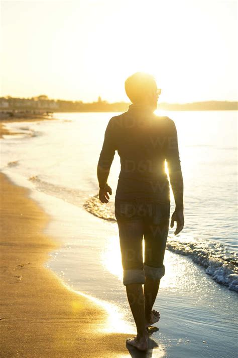 Silhouette Von Mann Zu Fuß Am Strand Bei Sonnenuntergang Lizenzfreies Stockfoto