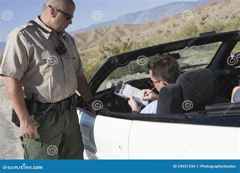 Man Writing On Ticket With Traffic Officer Standing By Car Stock Photo