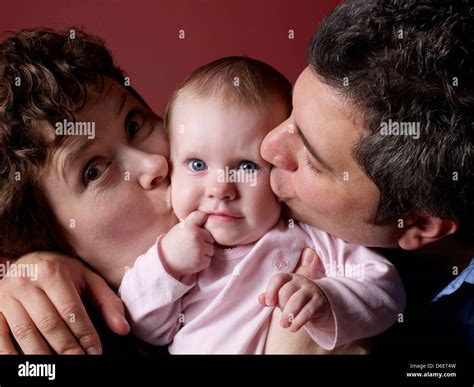 Parents Kissing Babys Cheeks Stock Photo Alamy