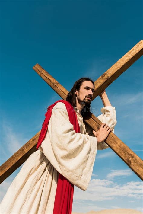 Angle View Of Jesus Holding Cross Against Blue Sky Stock Photo Image