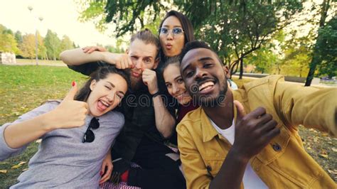 Multiracial Group Of Friends Is Taking Selfie In Park Sitting On Blanket Posing And Looking At