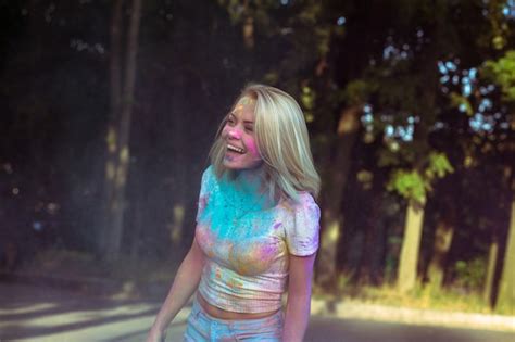 Premium Photo Smiling Blonde Woman With Fluttering Hair Playing With Holi Powder Exploding