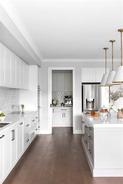 A Large Kitchen With White Cabinets And Wood Flooring On The Walls