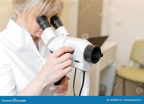 Female Blond Doctor Gynecologist Looks Through A Colposcope Examination By A Gynecologist Stock