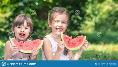 Two Little Cute Girls Eating Watermelon Outdoors Stock