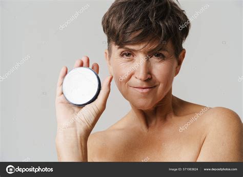 Madura Mujer Semidesnuda Sonriendo Mientras Muestra Crema Facial Aislada Sobre Fotograf A De