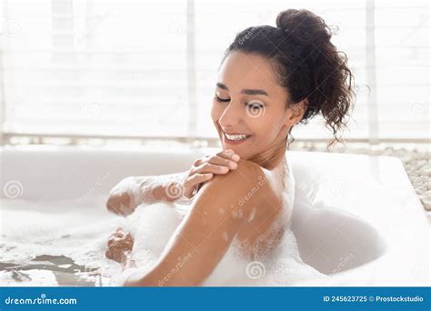Lovely Millennial Woman Lying In Bathtub With Foam Enjoying Bubble Bath Touching Soft Silky