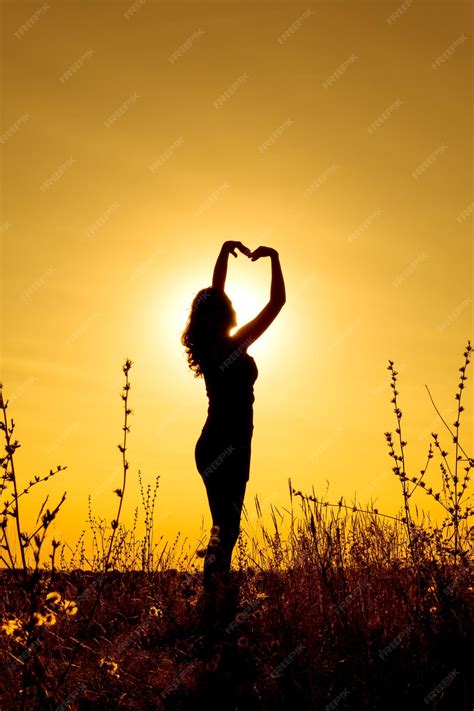 Premium Photo Silhouette Of A Girl At Sunset In A Field Holding Her Hands Above Her Head In
