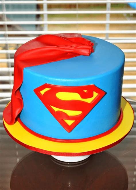 A Superman Cake On A Table In Front Of A Window