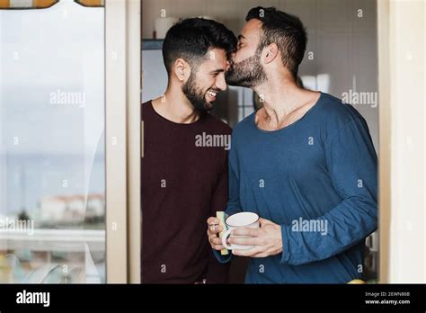 Gay Male Couple Having Tender Moment While Washing Dishes Inside Home Kitchen Focus On Faces