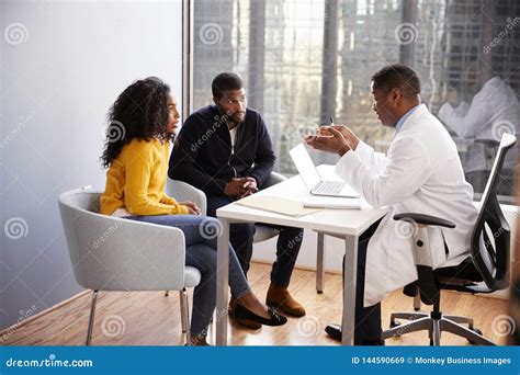 Couple Having Consultation With Male Doctor In Hospital Office Stock