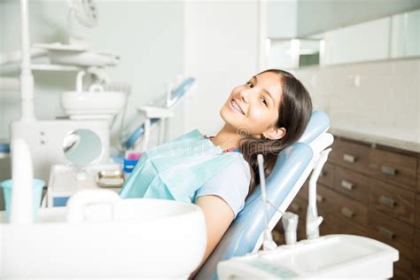 Portrait Of Smiling Girl With Braces Sitting At Clinic Stock Image