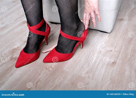 Woman In Black Fishnet Stockings Trying On Red Shoes On High Heels