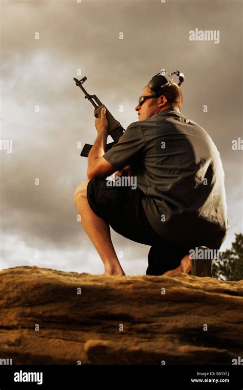 Man Holding Gun On Rocks Stock Photo Alamy