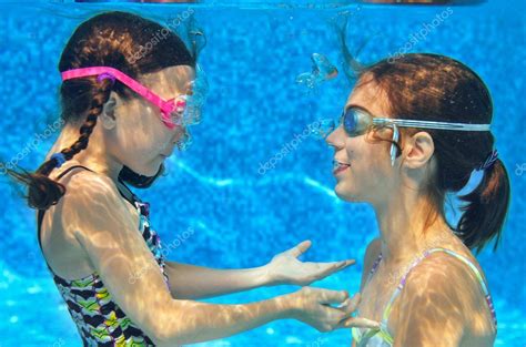Дети плавают в бассейне под водой счастливые активные девушки в очках