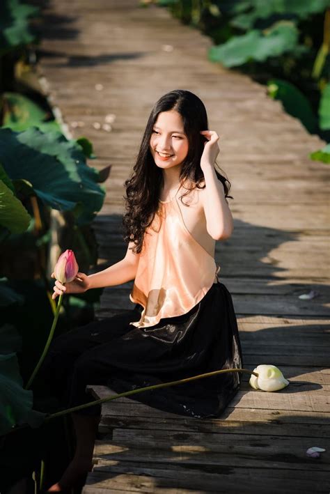 A Woman Sitting On A Wooden Walkway Holding A Flower