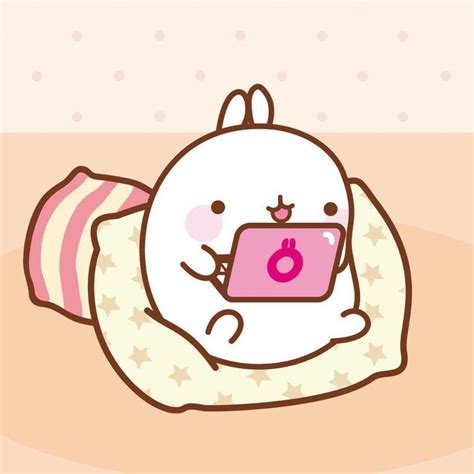 A White Bunny Holding A Pink Tablet On Top Of A Pillow In Front Of A Wall