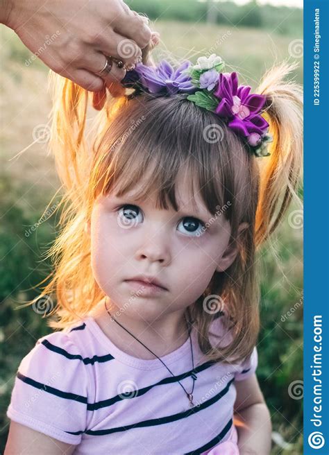 A Cute Girl With Flowers In Her Hair Stands In The Middle Of The Field