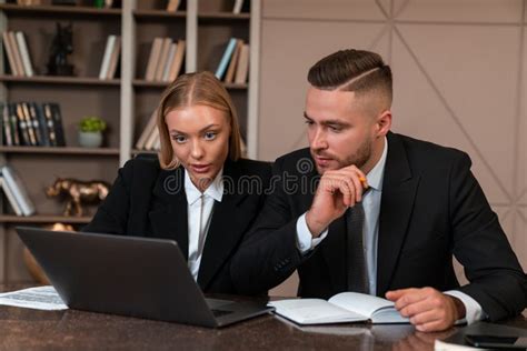 Two Business People Working Together Thoughtful Looking At Laptop