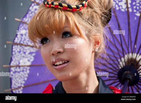 a japanese woman wearing blue contact lenses preforms a dance with a traditional parasol stock