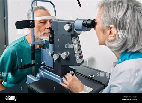 Experienced Optometrist Doing Sight Test For Senior Man At Modern