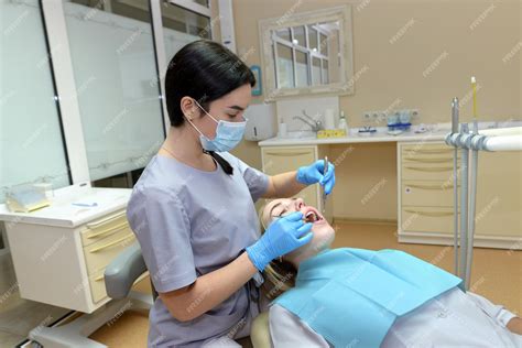 Uma Dentista Feminina Verifica Os Dentes De Uma Jovem Paciente O