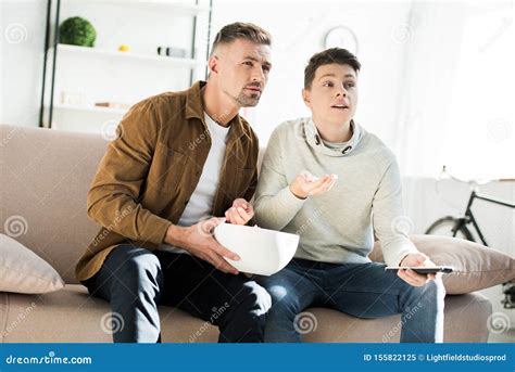 Padre Serio E Hijo Adolescente Viendo La Televisión Y Sosteniendo Un