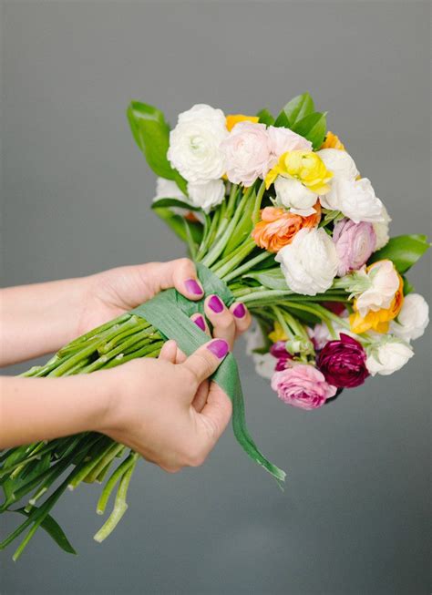 Blooms of yellow and white are loosely gathered with lush greenery inside a clear cylinder vase. How to Make a DIY Wedding Bouquet | A Practical Wedding