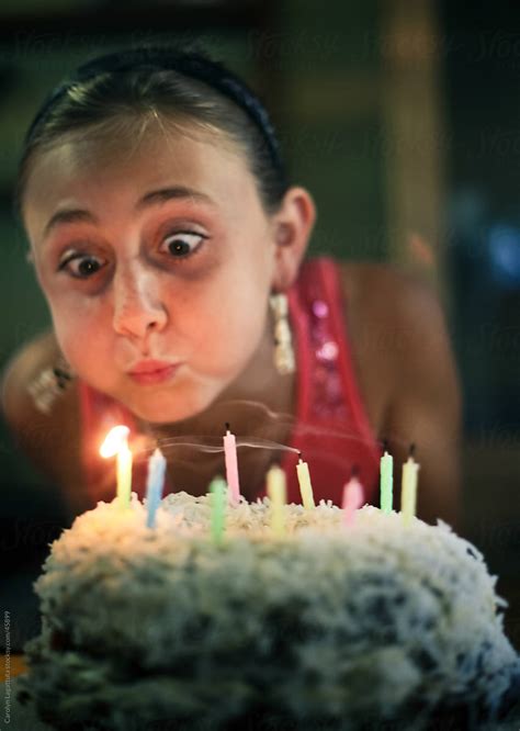 Girl With Wide Eyes And Puffy Cheeks Blowing Out Birthday Candles On A Cake Del Colaborador De