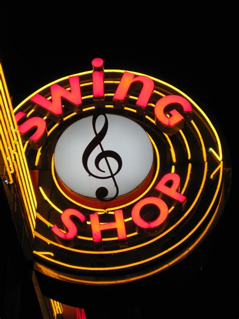 A Neon Sign That Says Swing Shop With A Treble