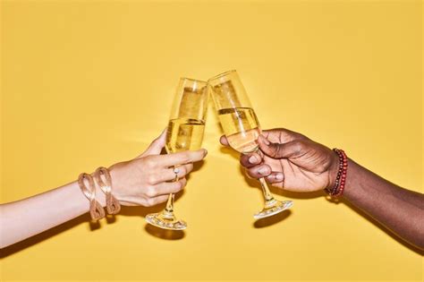 Premium Photo Two Hands Clinking Tall Champagne Glasses Against Yellow Background