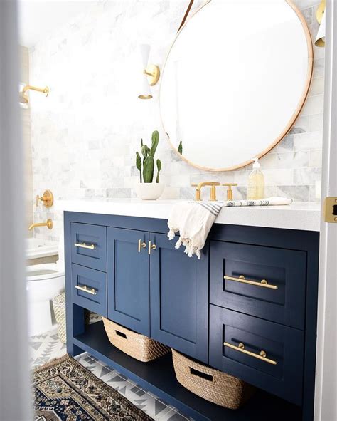 They are a lovely shade of navy blue, and the gold hardware matches the lights and shelf brackets. Modern bathroom design featuring a blue vanity and gold ...