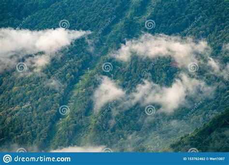 Clouds And Fog On The Slopes Of A Green Mountain With Cable Cars Stock